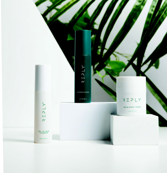 Skincare products with AIM REPLY Skincare Trio - Oil to Foam Cleanser, Essence/Toner, Day and Night Cream against a green leafy background