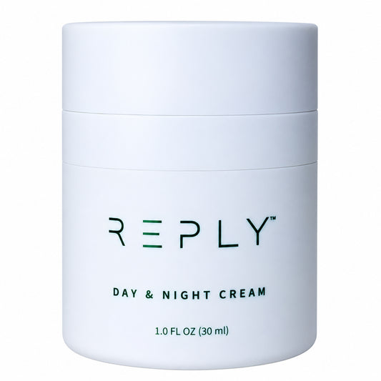 A white cylindrical cosmetic jar of AIM REPLY Day & Night Cream with dark green text on a clean white background.